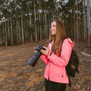 smiling-woman-holding-camera-in-forest